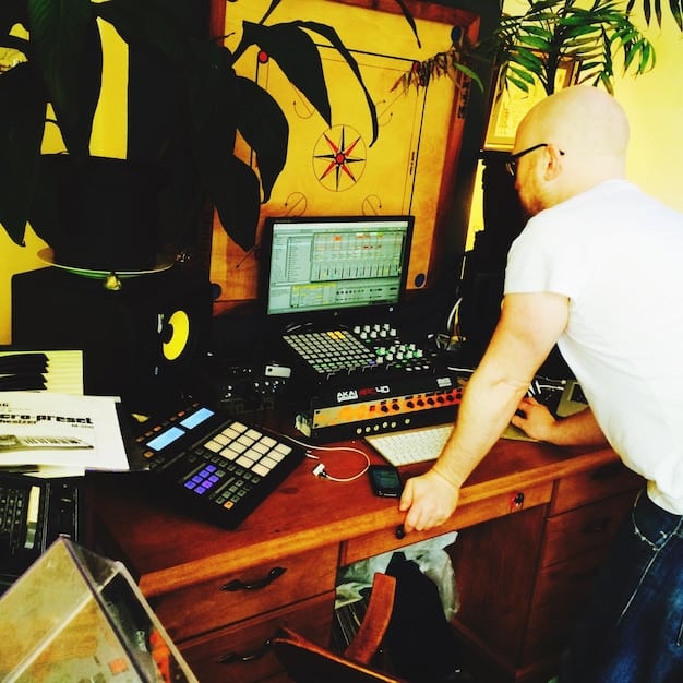 A behind-the-scenes shot of a sound designer in the 1970s working with analog equipment, including tape recorders and mixing consoles. The scene should be cluttered but focused, showcasing the hands-on, technical nature of sound design at the time.