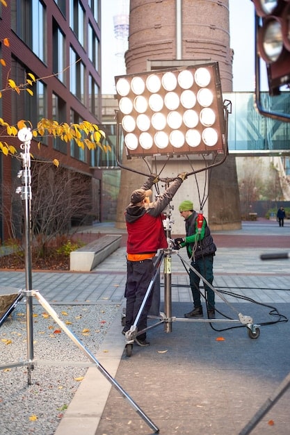 A bustling urban street scene with a small film crew setting up equipment for a shot. The location is a public space, and the crew is carefully arranging lights and cameras to capture the scene. The image showcases the challenges and excitement of filming on location.