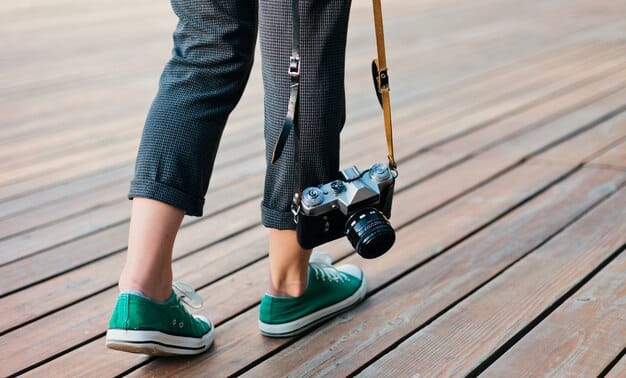 A filmmaker using a simple, home-made dolly system consisting of a wooden plank and skateboard wheels to achieve a smooth tracking shot, demonstrating cost-effective solutions on set.