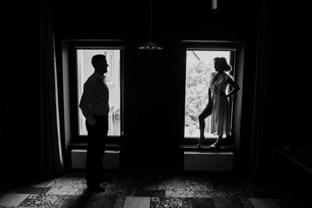 A black and white still from a European film, depicting a tense moment between two characters in a dimly lit room. The image conveys a sense of mystery and intrigue.