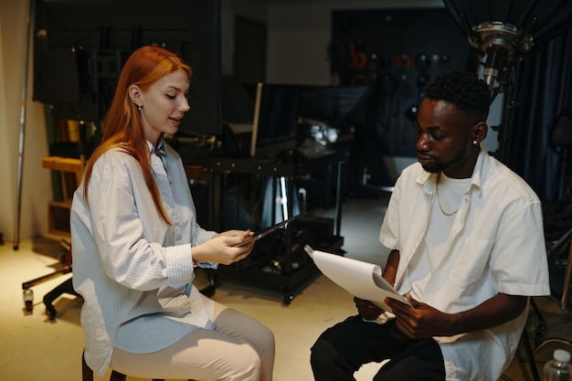 A filmmaker and a composer in a meeting, discussing the music for a short film. They are looking at a screen displaying the film's timeline, synchronized with musical cues. The caption is 'Discussing the role of music in short films: how to choose the right score to enhance your story'.
