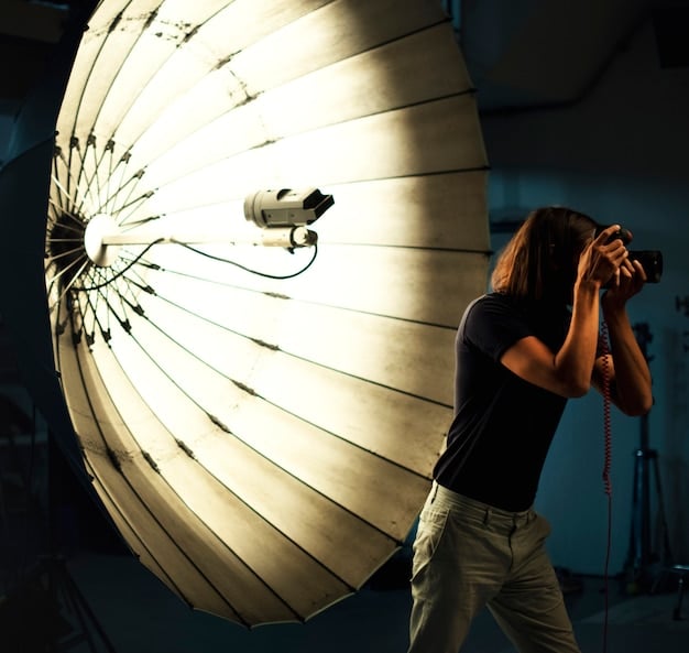 A close-up shot of a filmmaker adjusting a reflector to bounce sunlight onto an actor's face during an outdoor scene. The image highlights the use of simple tools for effective lighting in 'Short Film Cinematography: Achieving a Professional Look with Limited Resources'.